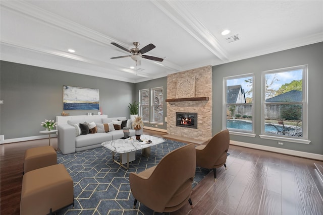 living room featuring dark wood-type flooring, beam ceiling, crown molding, ceiling fan, and a fireplace