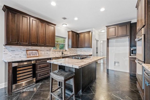 kitchen with sink, wine cooler, a center island, stainless steel appliances, and light stone countertops