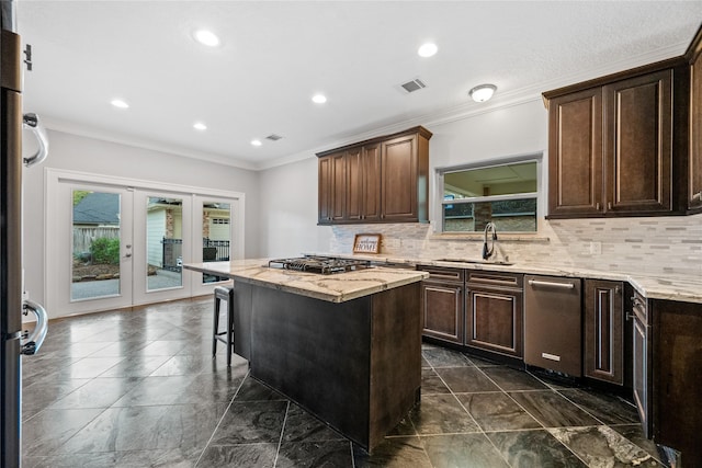 kitchen featuring a kitchen island, sink, a kitchen bar, gas stovetop, and french doors