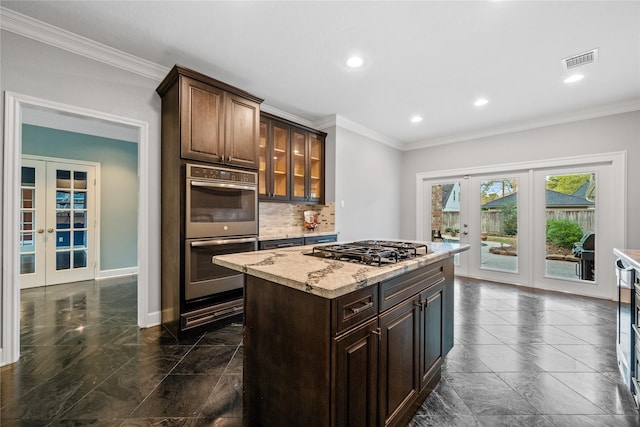 kitchen featuring french doors, gas stovetop, dark brown cabinets, a kitchen island, and stainless steel double oven