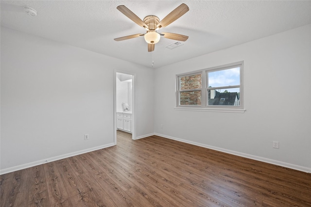 spare room with dark wood-type flooring, ceiling fan, and a textured ceiling