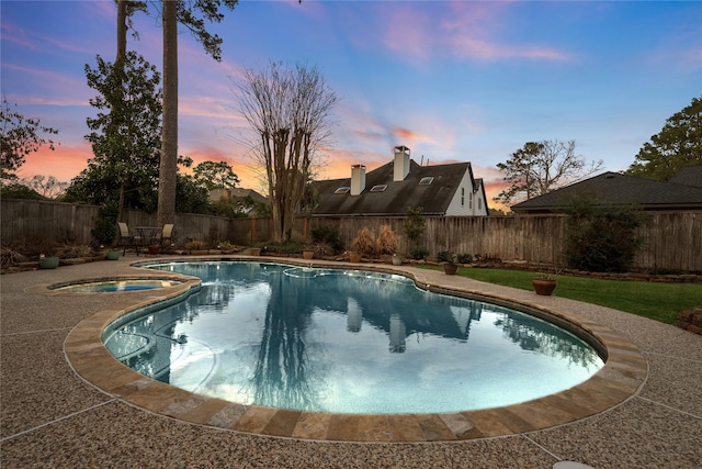 pool at dusk with an in ground hot tub