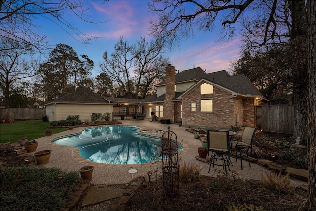 pool at dusk featuring an in ground hot tub and a patio