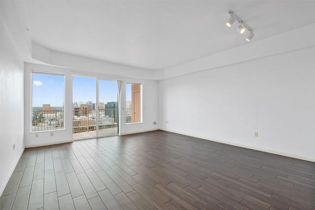 unfurnished room featuring dark wood-type flooring and rail lighting