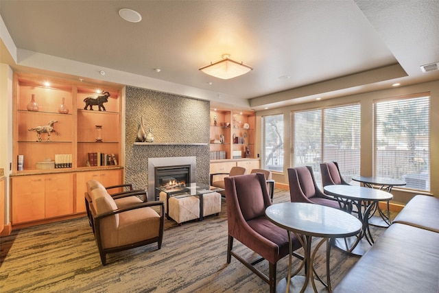 living room featuring a large fireplace, a raised ceiling, and built in features