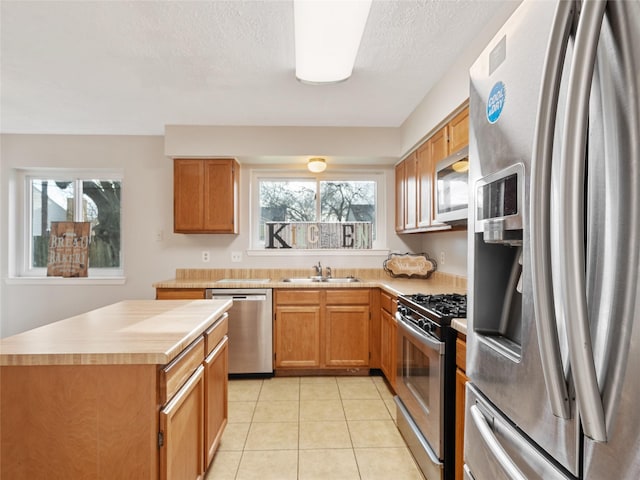 kitchen featuring sink, light tile patterned floors, a healthy amount of sunlight, and appliances with stainless steel finishes