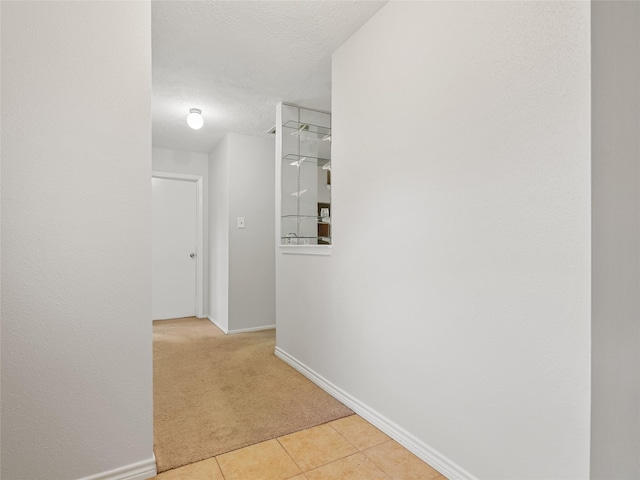 hallway with light carpet and a textured ceiling