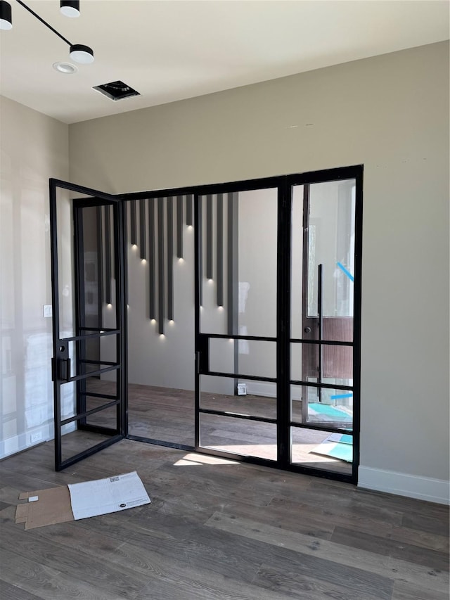 unfurnished room with dark wood-style floors, visible vents, and baseboards