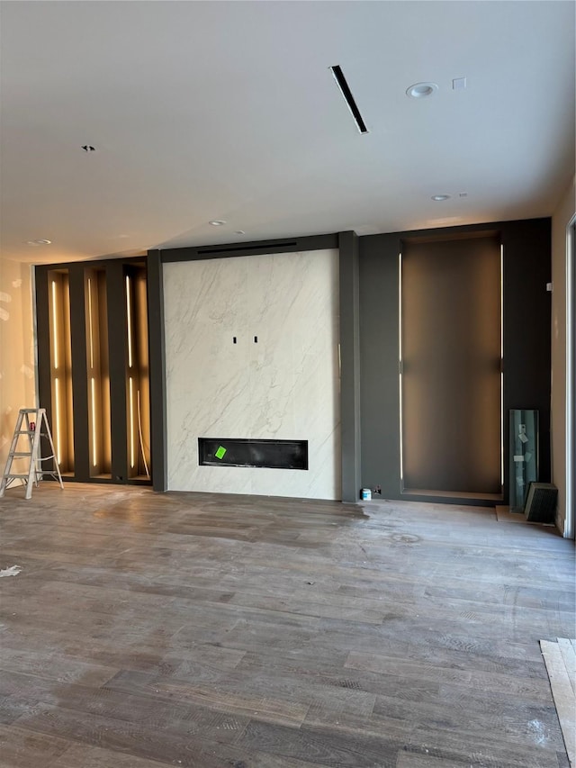 unfurnished living room featuring recessed lighting, a premium fireplace, and wood finished floors