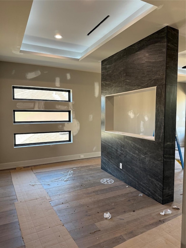 interior space featuring baseboards, a tray ceiling, wood finished floors, and recessed lighting