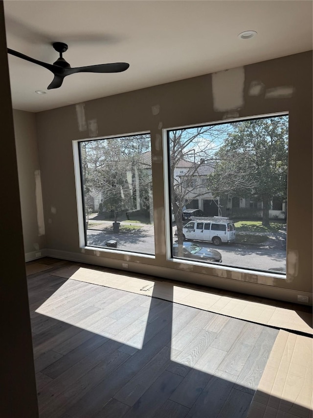 unfurnished room featuring ceiling fan, wood finished floors, and baseboards