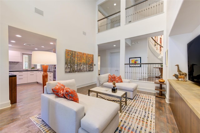 living room featuring wood finished floors, visible vents, baseboards, recessed lighting, and stairs