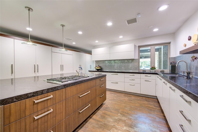 kitchen with modern cabinets, visible vents, stainless steel gas stovetop, and a sink