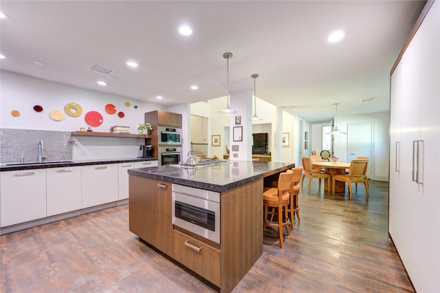 kitchen with modern cabinets, a sink, open shelves, a kitchen island, and a breakfast bar area