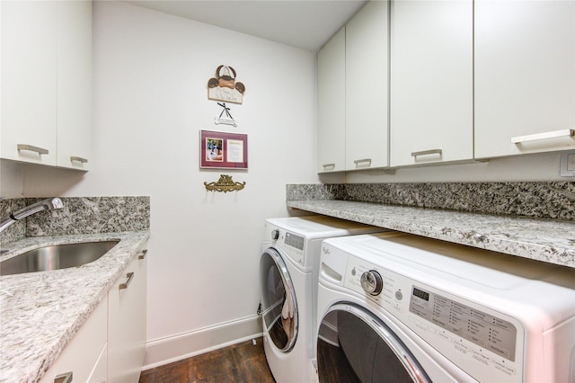 clothes washing area featuring a sink, dark wood-style floors, washing machine and dryer, cabinet space, and baseboards