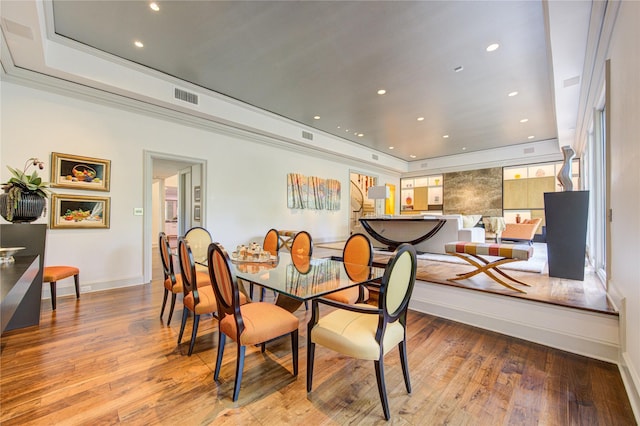 dining space with visible vents, recessed lighting, baseboards, wood-type flooring, and a raised ceiling