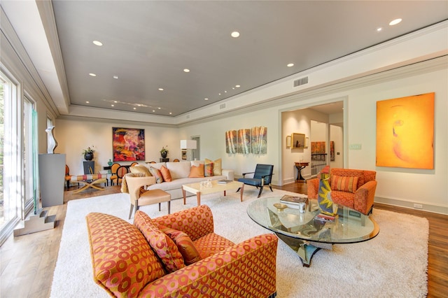 living room with wood finished floors, visible vents, baseboards, a tray ceiling, and recessed lighting