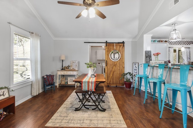 interior space featuring dark wood-type flooring, ornamental molding, a barn door, and washer / clothes dryer