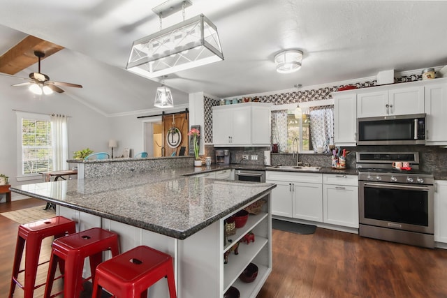 kitchen with stainless steel appliances, sink, a breakfast bar area, and decorative light fixtures