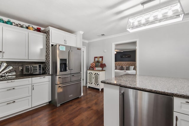 kitchen featuring dark stone countertops, high end refrigerator, white cabinets, decorative backsplash, and dark wood-type flooring