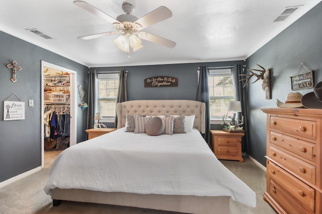 carpeted bedroom with multiple windows, a spacious closet, a closet, and ceiling fan