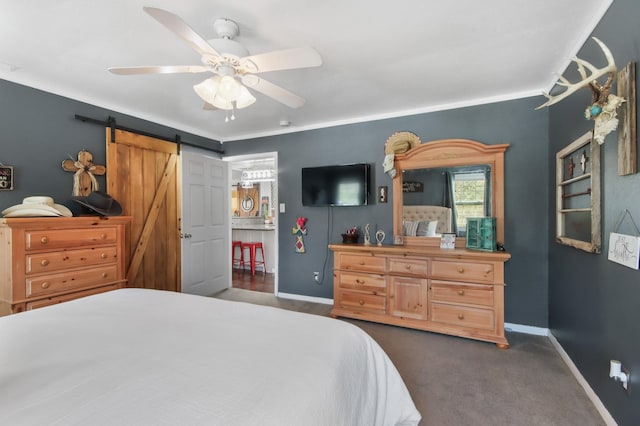 bedroom featuring a barn door, ceiling fan, and dark colored carpet