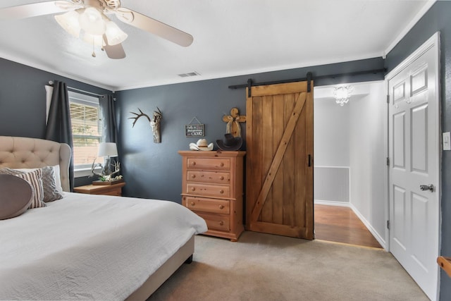 bedroom with a barn door, light carpet, and ceiling fan