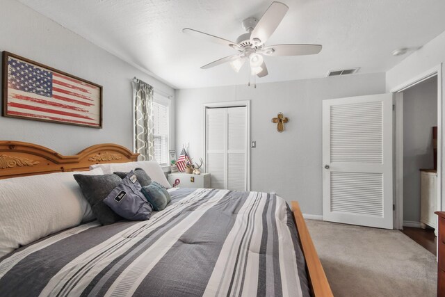 carpeted bedroom with ceiling fan and a closet