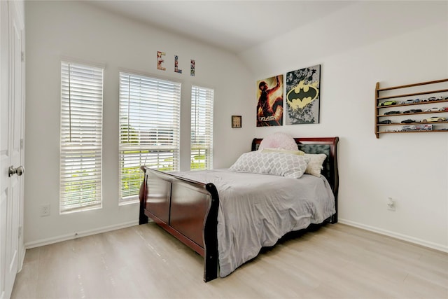 bedroom featuring vaulted ceiling, multiple windows, and light wood-type flooring