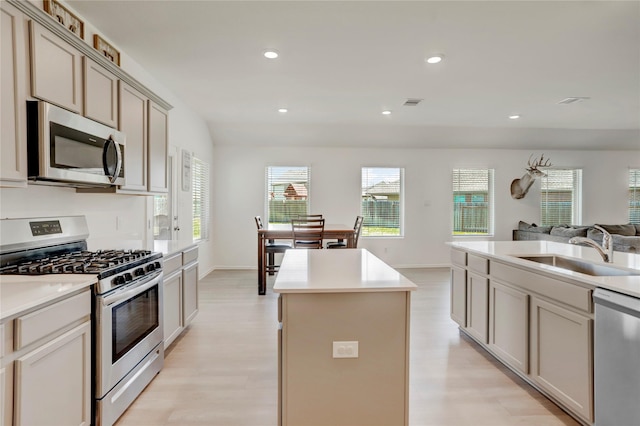 kitchen with sink, a kitchen island, light hardwood / wood-style floors, and appliances with stainless steel finishes