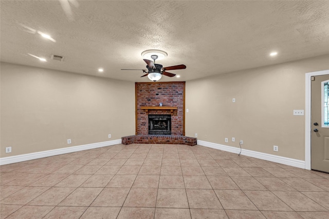 unfurnished living room featuring a brick fireplace, light tile patterned floors, a textured ceiling, and ceiling fan