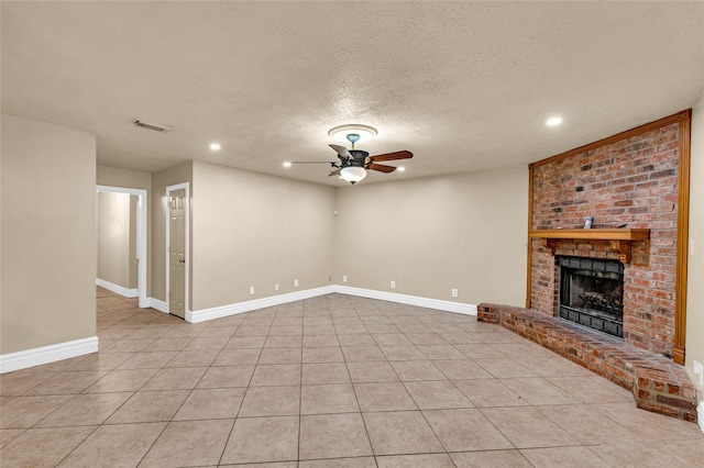 unfurnished living room featuring ceiling fan, light tile patterned floors, a textured ceiling, and a fireplace