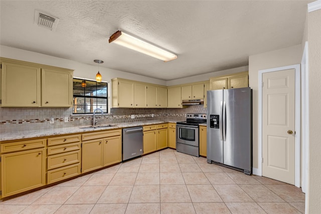 kitchen featuring light tile patterned flooring, sink, tasteful backsplash, decorative light fixtures, and appliances with stainless steel finishes