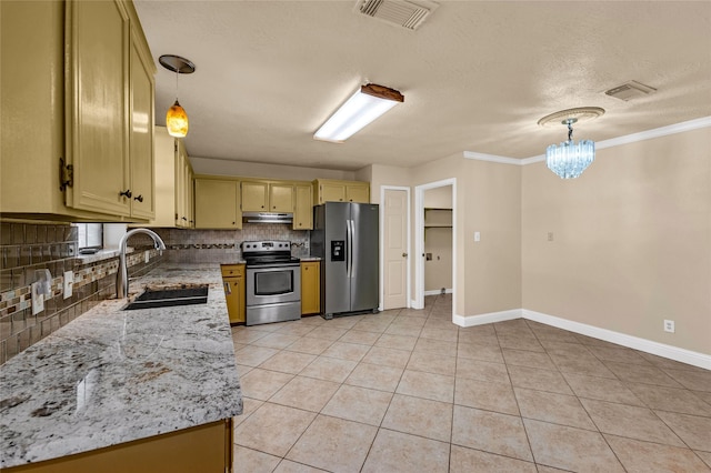 kitchen with sink, light stone counters, hanging light fixtures, appliances with stainless steel finishes, and decorative backsplash