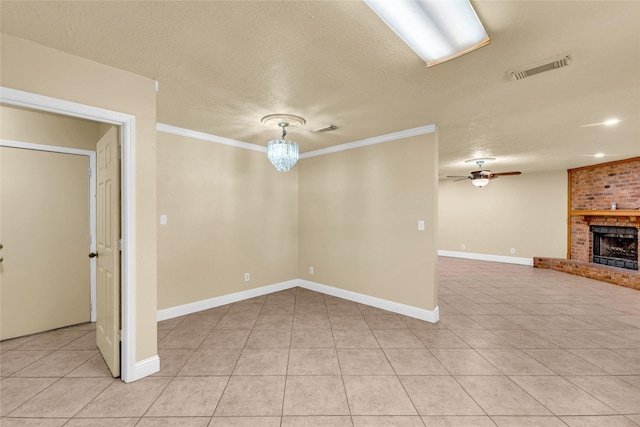 tiled empty room featuring ceiling fan with notable chandelier, a fireplace, ornamental molding, and a textured ceiling