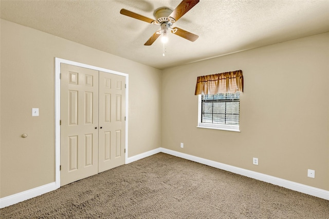 unfurnished bedroom with ceiling fan, carpet flooring, a closet, and a textured ceiling