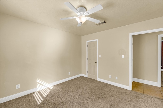 carpeted empty room featuring ceiling fan and a textured ceiling