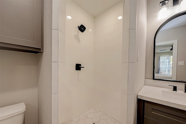 bathroom with vanity, tiled shower, and toilet