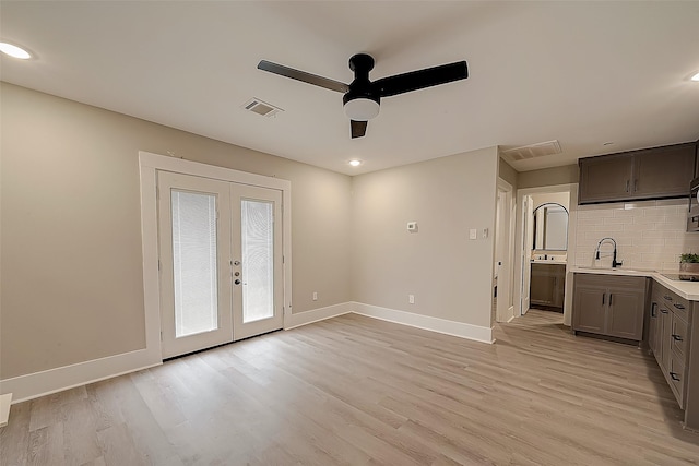 interior space featuring french doors, sink, decorative backsplash, and light hardwood / wood-style flooring