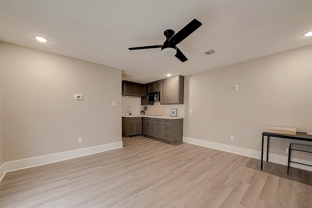 unfurnished living room with sink, ceiling fan, and light wood-type flooring