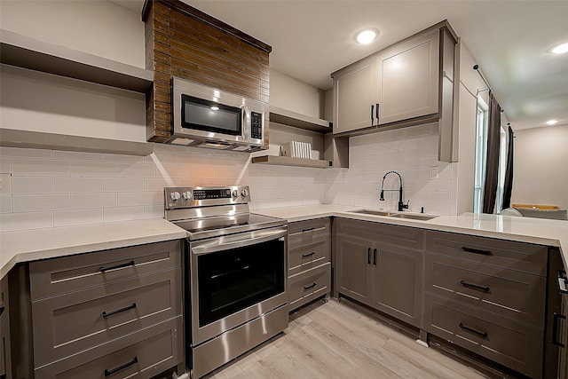 kitchen with stainless steel appliances, gray cabinets, sink, and backsplash