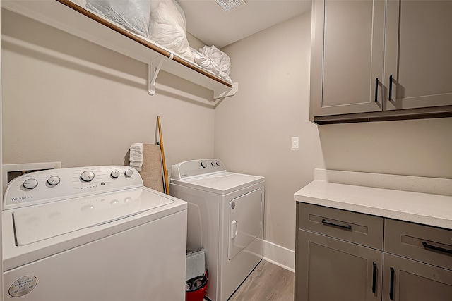 laundry room with cabinets, washer and dryer, and light wood-type flooring