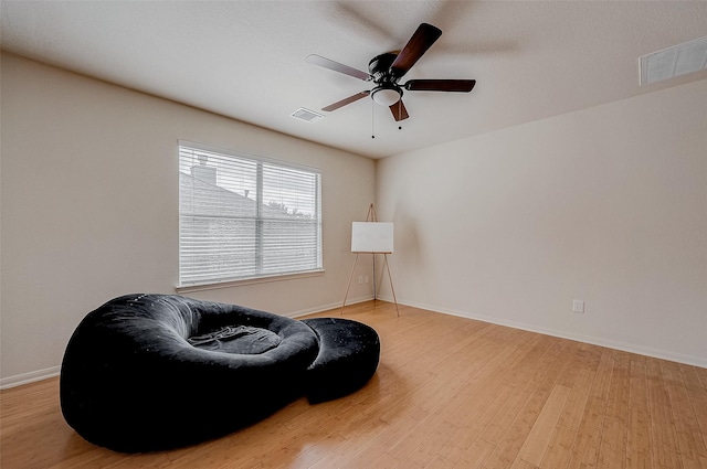 living area featuring hardwood / wood-style flooring and ceiling fan