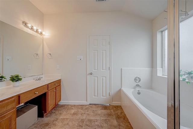 bathroom featuring a healthy amount of sunlight, vaulted ceiling, vanity, and a tub