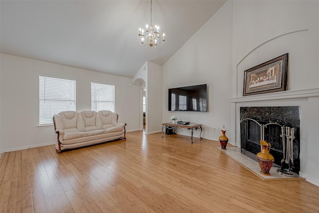 living room featuring an inviting chandelier, a fireplace, high vaulted ceiling, and light wood-type flooring