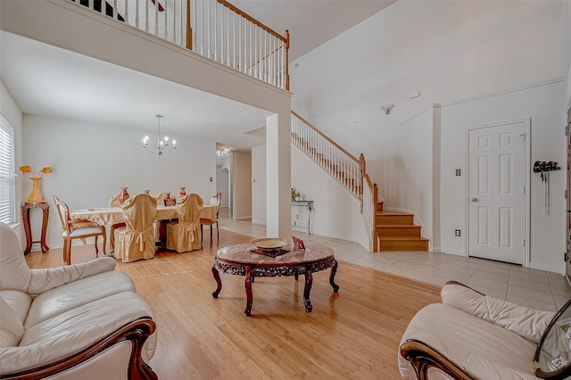 living room featuring a towering ceiling, light hardwood / wood-style flooring, and a notable chandelier