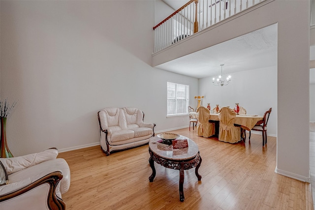 living room featuring a high ceiling, a notable chandelier, and light hardwood / wood-style flooring