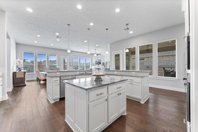 kitchen with a kitchen island, decorative light fixtures, dishwasher, light stone counters, and kitchen peninsula