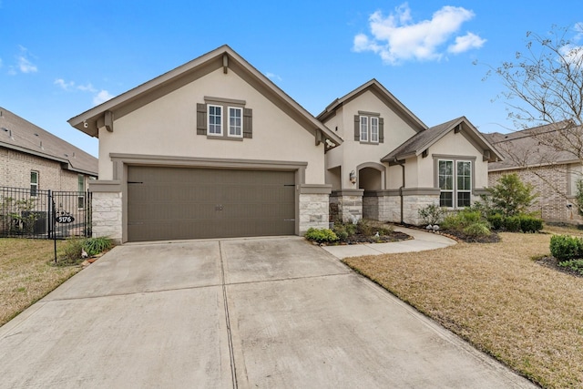 view of front of property featuring stucco siding, stone siding, driveway, and fence