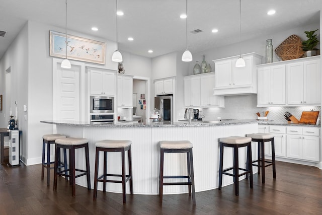 kitchen with decorative light fixtures, white cabinets, a kitchen bar, a large island, and stainless steel appliances